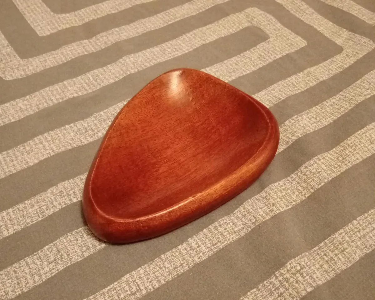 A wooden trinket dish photographed on a sofa, lit by a ceiling light